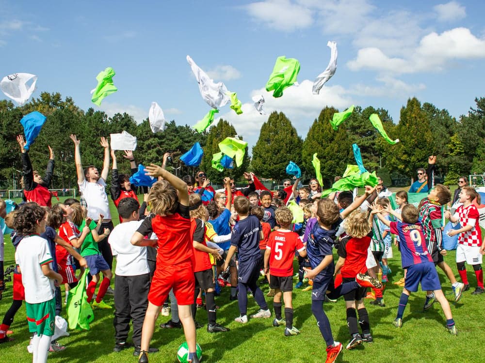 Children celebrating on the pitch with colorful fabrics in the air